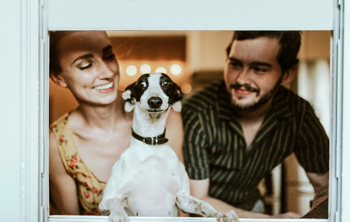 Two smiling owners with their dog between them